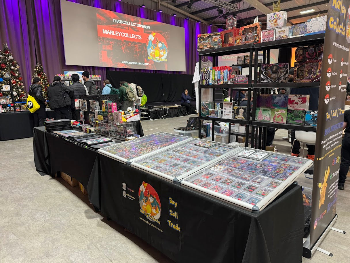 Marley Collects display of trading card games at a convention with a large screen in the background.