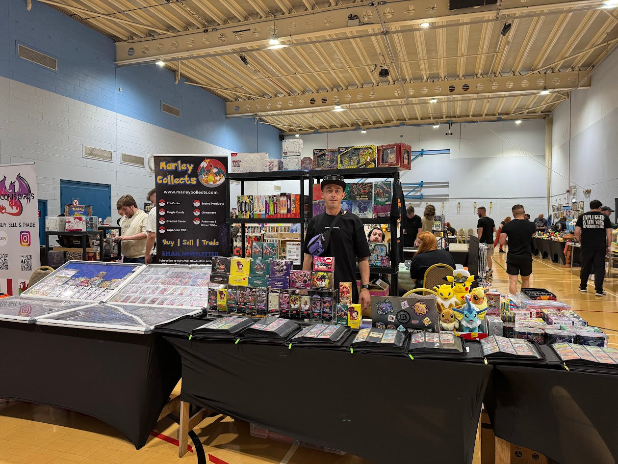Ben Smedley, Owner of Marley Collects standing behind a table with collectibles at a convention center.